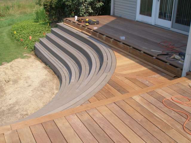 Outdoor deck with step down and circular treaded stairs complement this backyard landscape design.